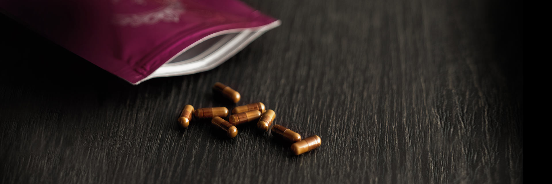 母の雫プラセンタEXを木のテーブルに横たえて置いてあり、数粒袋から出ている画像2